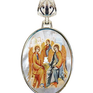 May include: A silver oval pendant necklace with a mother of pearl inlay featuring a religious icon of three angels with golden wings. The angels are depicted in a seated position with a blue and gold background.