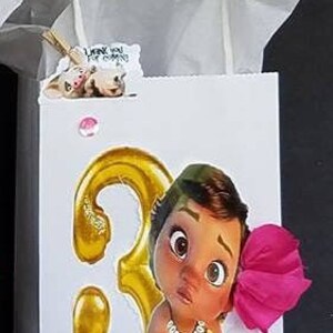 May include: White gift bag with a gold number 3, a pink flower, and a cartoon image of a brown-skinned baby girl. The bag has a white handle and the text "Set #3" is written on the front.