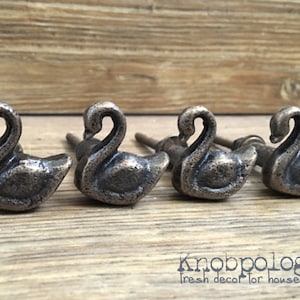 May include: Four antique silver swan-shaped cabinet knobs with a screw back.