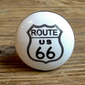 Könnte beinhalten: Weißer Keramik-Knopf mit einem schwarz-weißen Design eines Route US 66-Schilds.