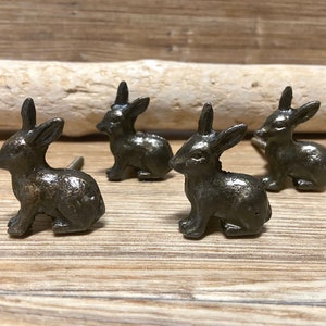 May include: Four antique bronze rabbit drawer pulls. The rabbit figurines are in a sitting position with their ears upright. The pulls have a screw on the back for attaching to a drawer.