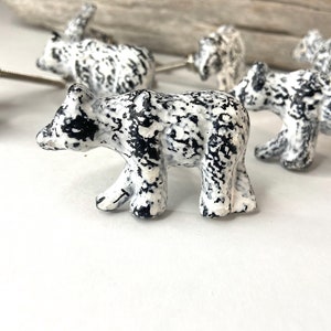 Puede incluir: Un juego de tiradores de cajones de cerámica en blanco y negro con forma de oso. Los osos están de pie y tienen un acabado moteado.