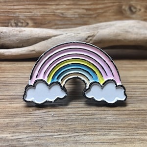 May include: A rainbow enamel pin with a pink, yellow, blue, and green rainbow with white clouds on either side.