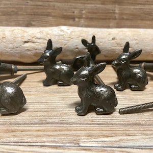 May include: Six antique bronze rabbit drawer pulls with a screw on the back. The rabbit pulls are in various poses and have a rustic finish.