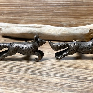 May include: Two silver fox-shaped cabinet knobs with a textured finish. The foxes are in a running position with their tails curled behind them.