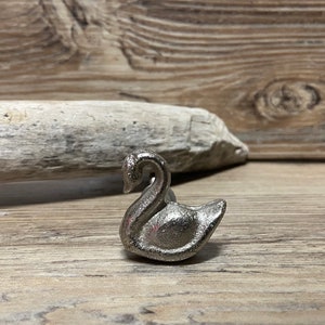 May include: Silver swan-shaped cabinet knob or drawer pull. The swan has a detailed design and a smooth, metallic finish.