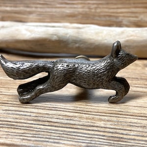 May include: A silver metal fox figurine door pull. The fox is in a running position with its tail curled behind it.