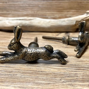 May include: Two antique bronze rabbit drawer pulls. The rabbit pulls are in a running position with a detailed design.