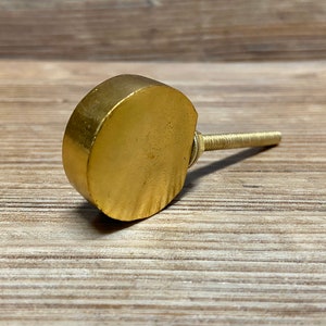 Puede incluir: Un pomo de armario dorado en forma de media luna con un tornillo roscado. El pomo está hecho de metal macizo y tiene una superficie ligeramente texturizada. El herraje está diseñado para muebles y decoración del hogar.