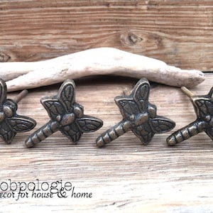 May include: Set of four antique bronze dragonfly cabinet knobs. Each knob features a detailed dragonfly design with a textured finish.