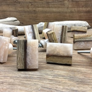 May include: A collection of rectangular cabinet knobs featuring a combination of natural dark brown wood and a translucent, pearlescent off-white resin material. Each knob includes a metal screw attachment and a small, matching resin spacer.