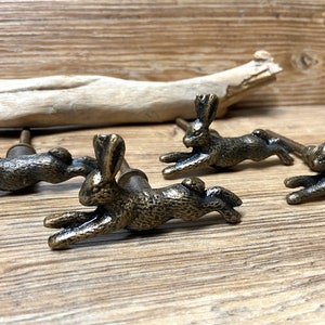 May include: Four antique gold-toned rabbit drawer pulls. Each pull features a detailed rabbit design with a raised tail and ears.