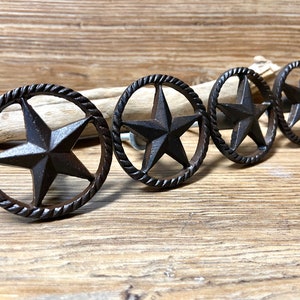 Könnte beinhalten: Vier rustikale braune Metall-Schrankknöpfe mit einem Seil-Design und einem fünfzackigen Stern in der Mitte.