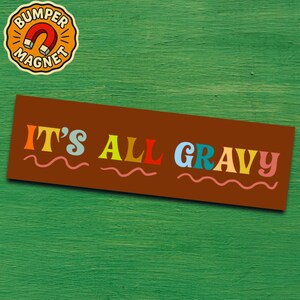 May include: A brown bumper magnet with the phrase "IT'S ALL GRAVY" in colorful, retro-style lettering. A wavy pink line underlines the words. The magnet is rectangular and has a circular "BUMPER MAGNET" logo in the upper left corner.
