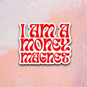 May include: White sticker with red text that reads "I am a money magnet" in a retro font.