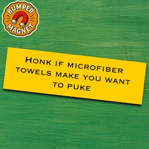 Puede incluir: Una pegatina amarilla con texto negro: "TOCA LA BOCINA SI LAS TOALLAS DE MICROFIBRA TE DAN GANAS DE VOMITAR". Un imán redondo con "BUMPER MAGNET" y un gráfico de herradura está en la esquina superior izquierda. El fondo es verde.