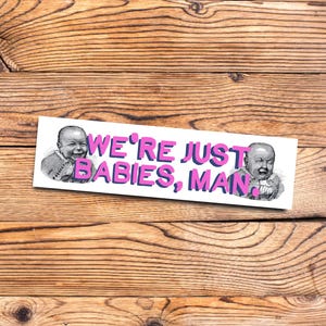 May include: A white sticker with a pink text overlay that reads "WE'RE JUST BABIES, MAN."  Two black and white images of babies are on either side of the text.