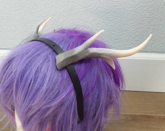 May include: A purple wig with a black headband and two white and gray antlers attached to the headband.