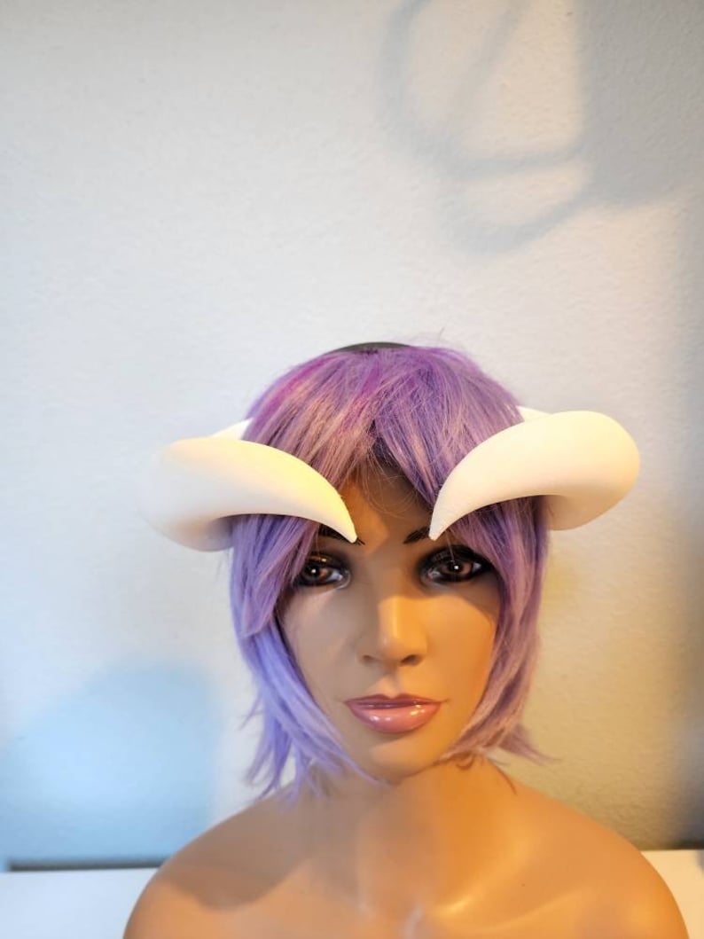 May include: White foam horns headband for cosplay or costume. The headband is worn on a purple wig.