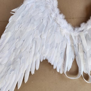 May include: White angel wings with a fluffy texture and white straps for attaching to a costume.