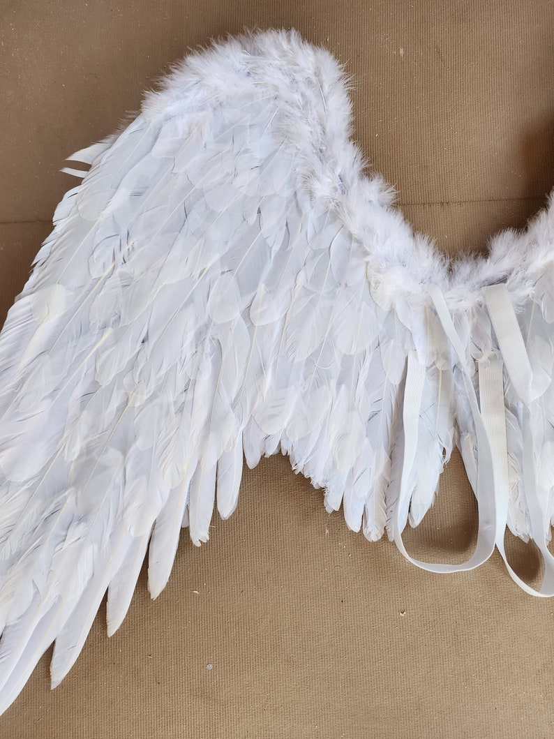 May include: White angel wings with a fluffy texture and white straps for attaching to a costume.