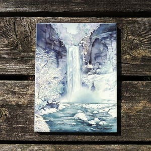 May include: Watercolor painting of a frozen waterfall cascading down a cliff face. The water is a light blue and the cliff is a dark gray. The painting is signed "Cheryl Chalmers" in the bottom right corner.
