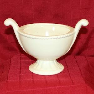 May include: A white ceramic planter with two handles, a round bowl, and a pedestal base.