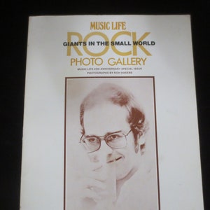 May include: A magazine cover with the title "Music Life" and the words "Giants in the Small World" and "Rock Photo Gallery". The cover features a black and white photo of a man wearing glasses.