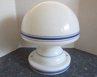 May include: White ceramic ceiling light fixture with a mushroom-shaped shade and blue stripes. The base of the light fixture has a blue stripe around the edge.