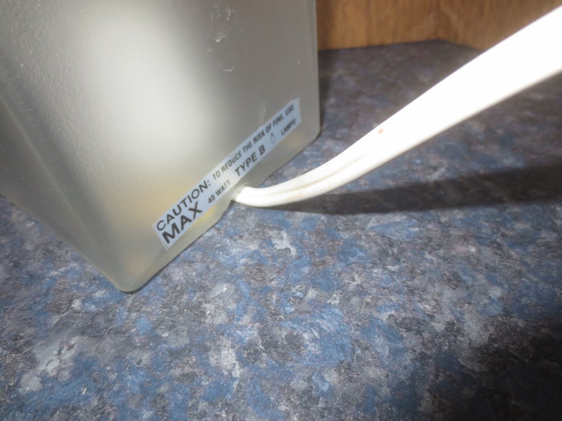 May include: Close-up of a white lamp base with a warning label that reads "CAUTION: TO REDUCE THE RISK OF FIRE, USE 40 WATT MAX TYPE B LAMP".