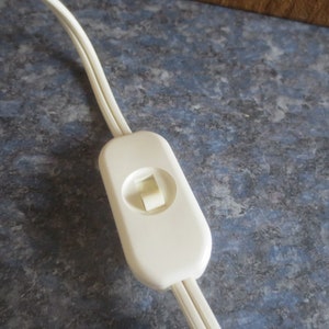 May include: A white inline on/off switch with a white cord attached.