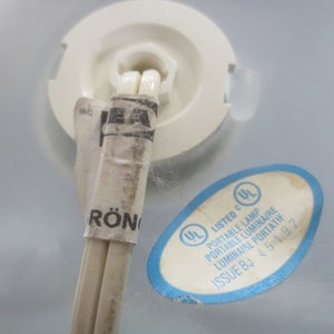 May include: A close-up of a white electrical cord with a white and black UL listed label. The label reads "Listed c UL Portable Lamp Portable Luminaire Luminaire Portatif Issue BJ 45 197".