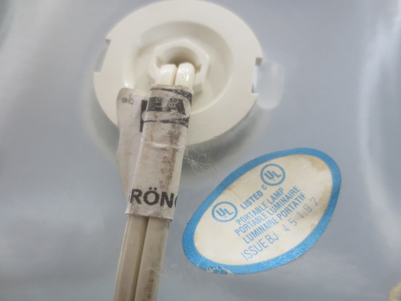 May include: A close-up of a white electrical cord with a white and black UL listed label. The label reads "Listed c UL Portable Lamp Portable Luminaire Luminaire Portatif Issue BJ 45 197".