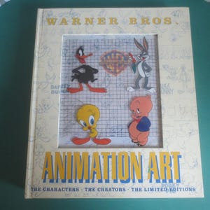 May include: A Warner Bros. Animation Art book featuring characters like Daffy Duck, Bugs Bunny, Tweety Bird, and Porky Pig. The book cover features a grid with illustrations of the characters.