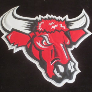 May include: Embroidered patch featuring a red bull head with white horns and accents. The bull has an angry expression, with a white and gray outline. The patch is on a black background. Ideal for jackets, bags, or other apparel.