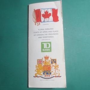May include: A white pamphlet featuring the Canadian flag and the text "CANADA". The pamphlet includes information on floral emblems, coats of arms, and flags of Canada, the provinces, and territories. The TD Bank logo is also visible.