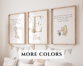 May include: Three framed Winnie the Pooh art prints. The prints feature quotes and illustrations of Winnie the Pooh and friends. The frames are light brown, and the prints are displayed on a white wall. A banner with gray and white triangles hangs below the prints.