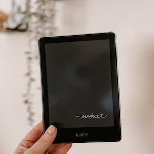 May include: A black Kindle e-reader with a white inscription that says "candace" and the word "kindle" on the bottom.
