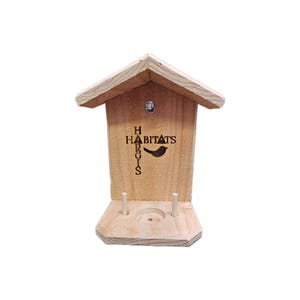 May include: A wooden bird feeder with a small bird silhouette and the text "HARGIS HABITATS" on the front. The feeder has two small dowels on the bottom for mounting.