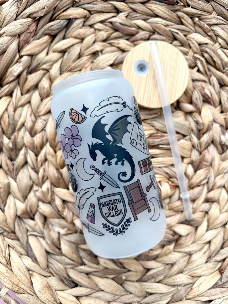 May include: A white frosted tumbler with a black dragon and other illustrations. The tumbler has a black and white shield with the text "Basgiath War College".