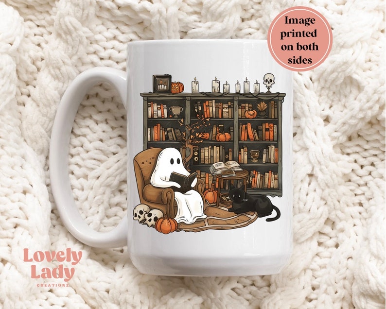May include: White ceramic mug with a black cat and a ghost reading a book in a library setting. The ghost is sitting in a chair with a book in its hand. The cat is sitting on the floor next to the chair. The library has bookshelves filled with books and a few pumpkins on the shelves. The mug is printed on both sides.