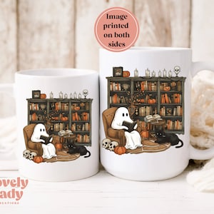 May include: Two white ceramic mugs with a design of a ghost reading a book in a library setting with bookshelves, pumpkins, and a black cat. The image is printed on both sides of the mug.