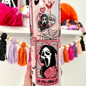 May include: A pink and white stainless steel tumbler with a graphic of a ghost wearing a mask and holding a phone. The tumbler has a pink straw and the text "No you hang up" on the bottom.