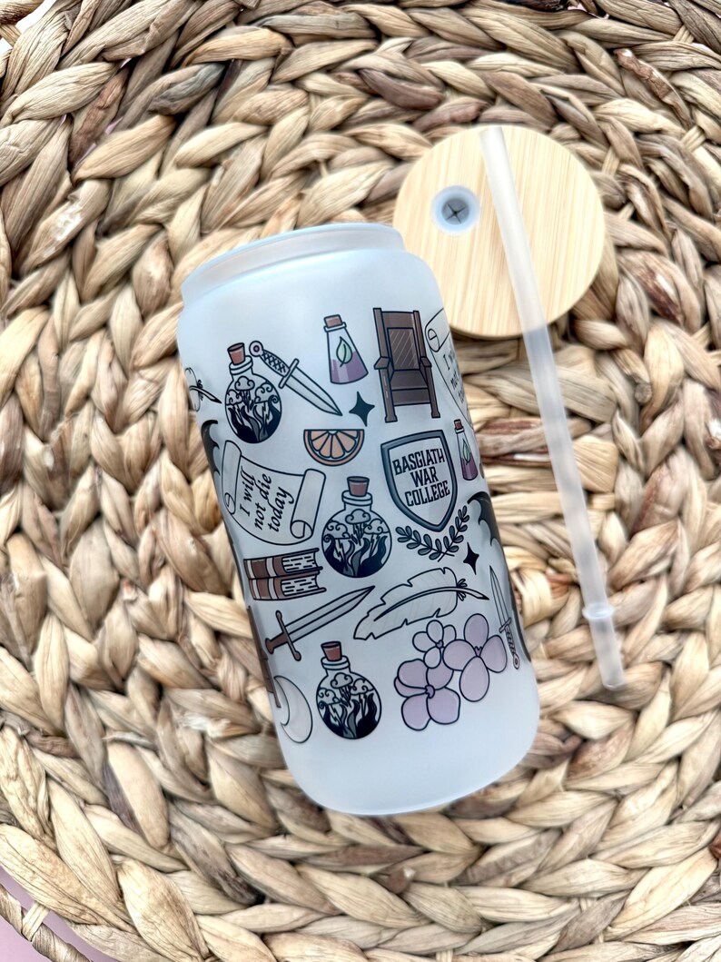 May include: A white frosted tumbler with a black and white design featuring a variety of illustrations including a potion bottle, a sword, a feather, a book, a crown, a lemon, and the text "I will not die today". The tumbler has a bamboo lid with a straw.
