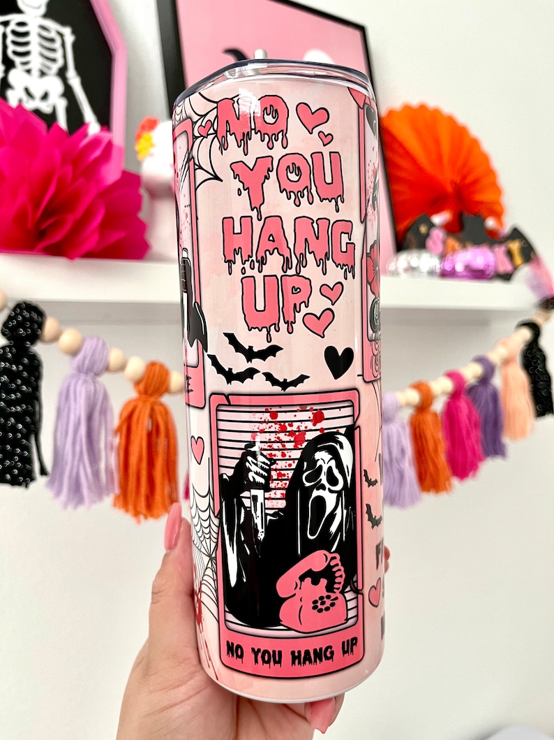 May include: Pink and black tumbler with a graphic of a ghost holding a phone and the text "No You Hang Up".