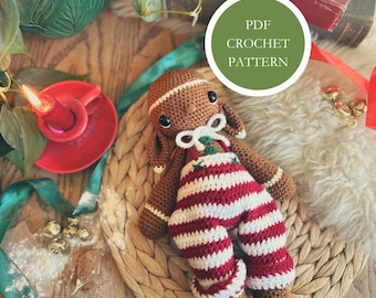 May include: A crocheted gingerbread man doll wearing red and white striped pants and a white bow tie. The doll is brown with black eyes and is lying on a woven mat. The image includes the text "PDF CROCHET PATTERN" in a green circle.