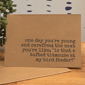 May include: A kraft paper greeting card with the text: "one day you're young and carefree; the next you're like, 'is that a tufted titmouse at my bird feeder?'" A second card is visible.