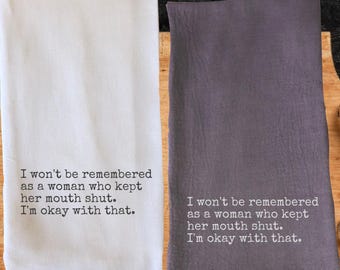 May include: Two kitchen towels, one white and one gray, with the same printed text in black. The text reads: "I won't be remembered as a woman who kept her mouth shut. I'm okay with that."