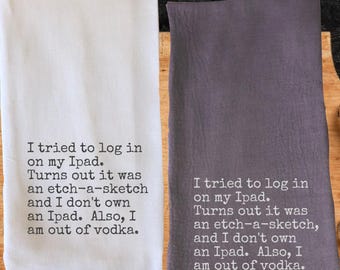 May include: Two kitchen towels, one white and one gray, with the same humorous text printed in black. The text reads: "I tried to log in on my iPad. Turns out it was an etch-a-sketch and I don't own an iPad. Also, I am out of vodka."
