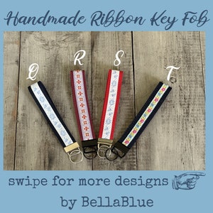 May include: Handmade ribbon key fobs in navy, burgundy, and red with floral and geometric patterns. Each fob has a metal ring and the letters Q, R, S, and T are visible. The text "swipe for more designs" and "by BellaBlue" are also present.